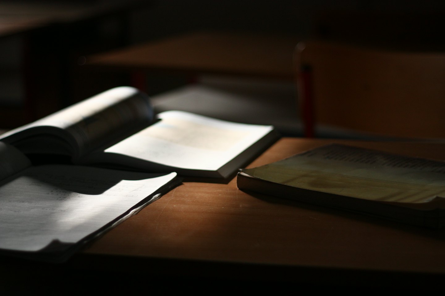 Three books rest on a wooden desk.