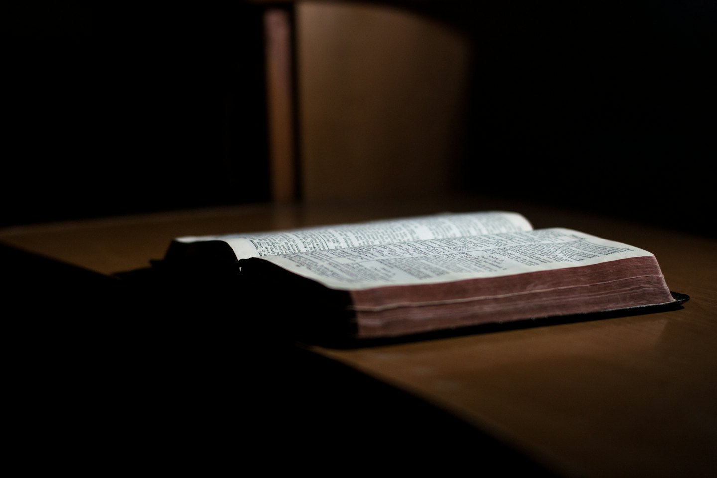 Open book with illuminated pages on dark wood.