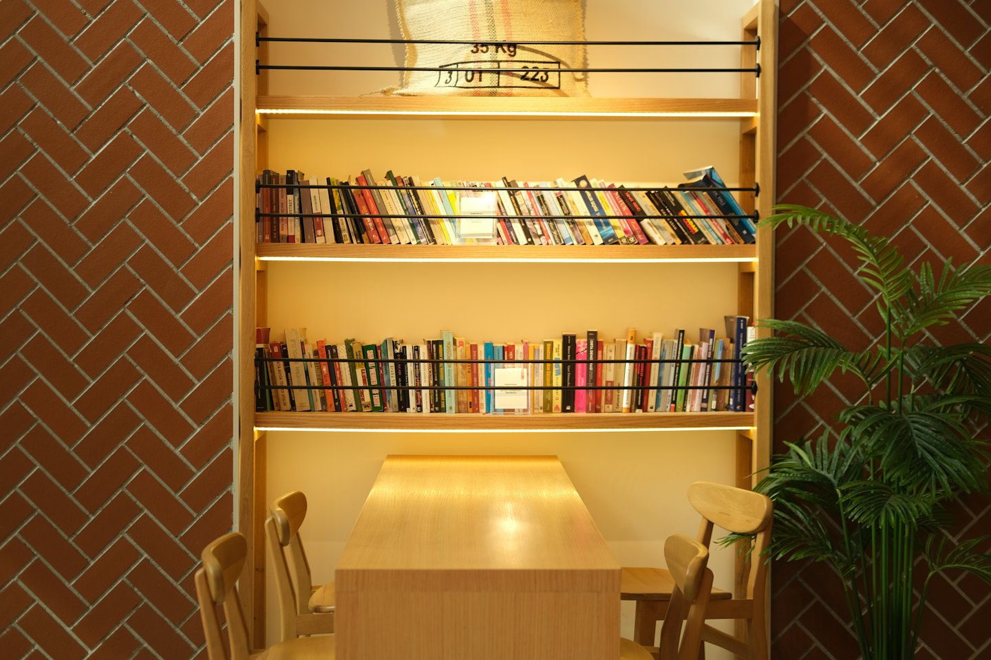 Bookshelf with a potted plant beside a cafe table.